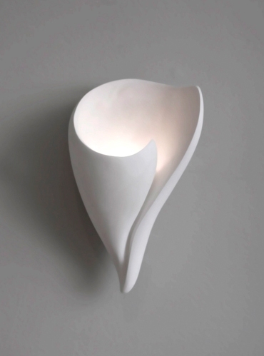 This pure plaster scultural form captures the essence of a shell. Sculpted by Hannah Woodhouse, it is a beautiful and elegant wall light for any home.